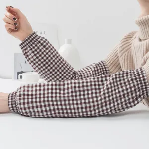 Detail shot of brown gingham cotton oversleeves, showing elastic cuffs and fabric texture.