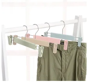 Plastic pants hangers detail showing adjustable clips and metal hooks holding green trousers.