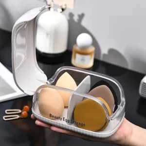 Boîte transparente pour éponge de maquillage avec couvercle anti-poussière et compartiments.
