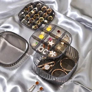 Multi-layer plastic jewelry storage box with compartments and lid for rings and earrings.