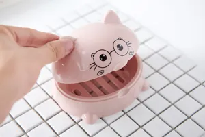 Pink plastic cartoon soap dish detail view with drainage layer and lid on white tile background.