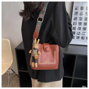 Retro bucket bag for women with colorful strap and cute bunny pendant, casual crossbody bag.