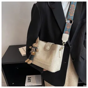 Detailed view of fashionable beige bucket bag with ethnic strap and cute rabbit pendant.