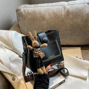 Black PU leather bucket bag with cute knitted rabbit charm, retro shoulder crossbody bag.