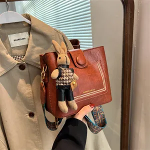 Brown vintage crossbody bag with cute rabbit plush pendant and wide retro strap for women