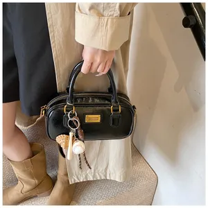 Black patent leather bowling bag for women, stylish vintage handbag with chic keychain charms.
