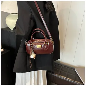 Detailed view of the dark brown patent leather vintage bowling handbag with chic charm and strap.