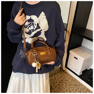 Brown retro bowling bag for women, stylish leather crossbody handbag with cute charms.