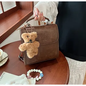 Detail view of the vintage brown backpack with cute fluffy bear charm and debossed lettering.