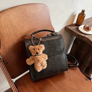 Retro vintage fashion casual backpack for students, stylish leather look with cute bear pendant.