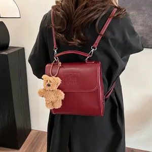 Vintage leather casual backpack for women, stylish school bag with cute bear pendant.