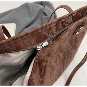 Detailed close-up view of brown vintage tote bag zipper and textured material, elegant style.