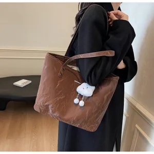 Close-up detail of the brown crinkled leather tote bag featuring a cute plush cloud charm.