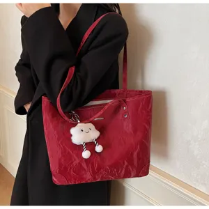 Detail view of the red vintage tote bag with cute cloud keychain, showing texture.
