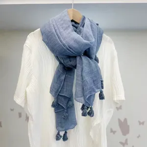 Detailansicht eines blauen Leinen-Schals mit Quasten, hängend auf einem weissen Hemd.