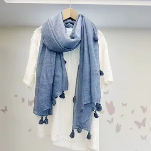 Nahaufnahme eines blauen Quastenschals auf weißem Oberteil, zeigt schöne weiche Textur.