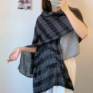 Detail view of stylish black and silver plaid scarf, elegant autumn accessory for women.