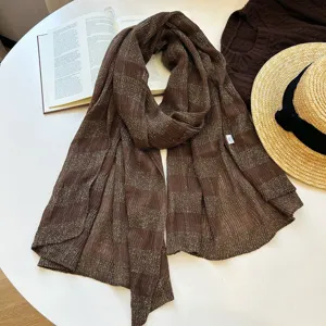 Detailed shot of a brown metallic striped knit scarf, perfect for autumn styling and casual wear.