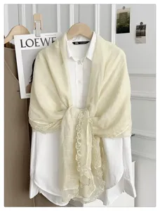 Detailopname van elegante crèmekleurige kanten sjaal met fijne rand, stijlvol lenteaccessoire.
