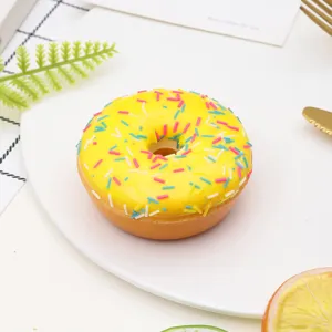 Macro view of a realistic yellow PU donut model with colorful sprinkles on a white plate.