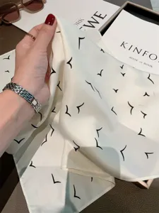 Silk square scarf detail showing smooth fabric and elegant abstract bird print in monochrome.