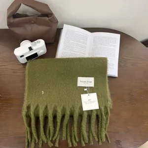 Gedetailleerd shot van een gezellige groene gebreide sjaal met franjes op een houten tafel.