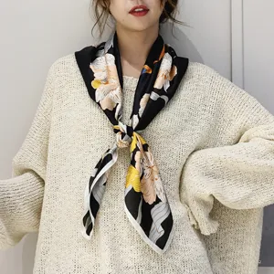 Vista dettagliata di un foulard quadrato in seta nera con stampa floreale, elegante accessorio.