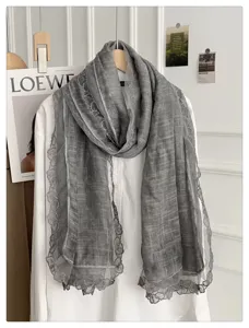 Detailopname van een stijlvolle grijze sjaal met kantrand, elegant accessoire voor dames.
