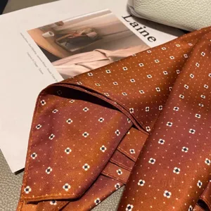 Detalle de pañuelo de seda marrón con elegante diseño de lunares para un look primaveral.