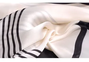 Detailansicht eines schicken Seidentuchs mit schwarz-weißen Streifen und eleganter Textur.