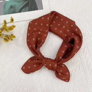 Vista detallada de pañuelo de seda marrón con lunares, ideal para estilo primaveril chic.