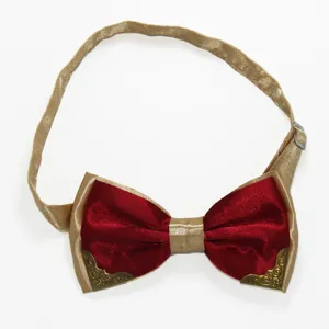 Detailed close-up view of red velvet bow tie featuring gold edges and vintage metal corner accents.