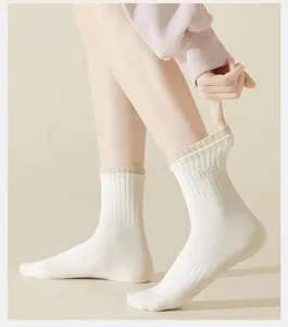 Detailed view of women's white mid-calf socks with ribbed cuffs, breathable cotton fabric.
