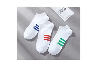 Primo piano dettagliato di calzini sportivi bianchi con eleganti strisce tricolori su sfondo grigio.