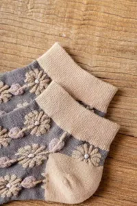 Close-up of vintage floral embroidered women socks showcasing exquisite textured vine patterns.
