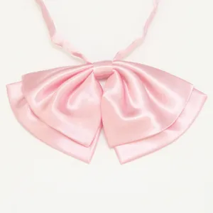 Dettaglio fiocco in raso rosa, consistenza liscia, accessorio perfetto per uniforme.