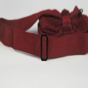 Detailed close-up of dark red knitted bow tie strap with adjustable black buckle.
