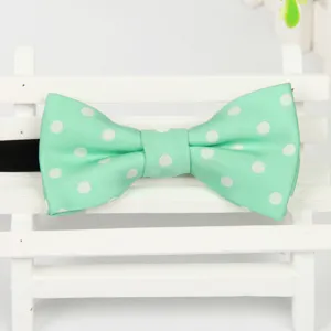 Gros plan detail de noeud papillon enfant vert menthe à pois sur un petit banc blanc.
