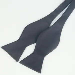 Close-up detail view of a solid black polyester self-tie bow tie for men formal business wear.