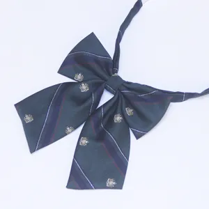 Detail shot of dark green plaid JK bow tie featuring elegant crown crest embroidery and smooth ribbon.