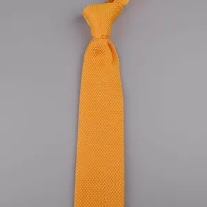 Primo piano della cravatta in maglia arancione con trama fine e design appuntito.