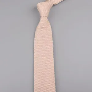 Primo piano sulla trama a maglia fine e sulla punta affilata di un elegante cravatta rosa chiaro.