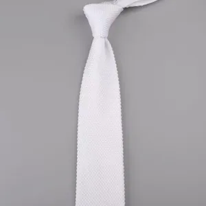 Vista dettagliata di una cravatta lavorata a maglia bianca, con punta classica e trama fine.