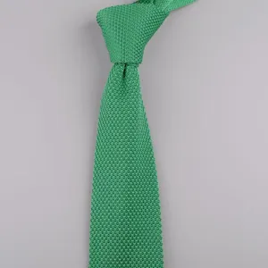 Primo piano di una cravatta in maglia verde con dettaglio della trama tessuta fine.