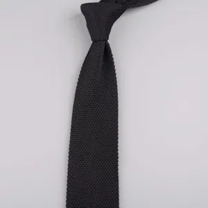 Dettaglio di una cravatte a maglia nera da uomo elegante con trama fine e design a punta.