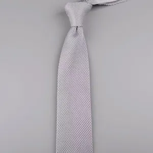 Dettaglio di cravatta in maglia grigio chiaro, larghezza 7cm, punta, stile casual elegante.