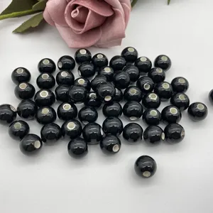 Black ceramic loose beads detail showing the smooth round shape and clean inner hole for DIY crafts.
