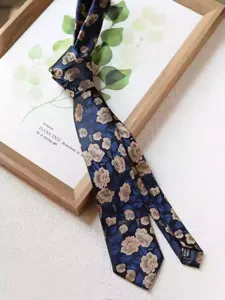 Detailed view of the elegant dark blue floral necktie, showing intricate gold flower patterns.