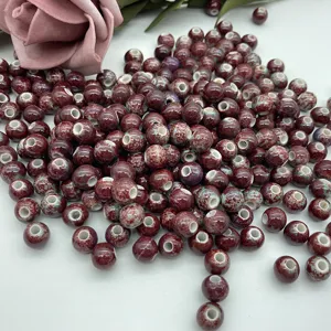 Detailed close-up view of scattered 8mm red ceramic loose beads featuring white holes for DIY crafts.