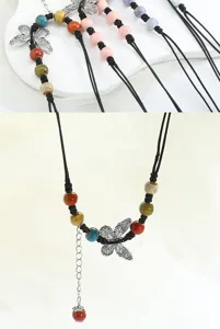 Detailed view of handmade ceramic butterfly necklace with multi-color beads and black cord.